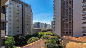 A high-rise building with multiple floors, a clear sky, and surrounding greenery. - Studio in Condo w/ Balcony in Jardins Hmj0309 (São Paulo)