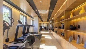 Ein Fitnessraum mit Laufbändern, Übungsbällen und Gewichten auf Holzböden.
