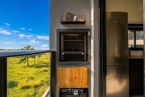 A modern kitchen with a built-in oven, a wooden panel, and a view of a grassy field. - Comfort in Condo w/ Pool in Campeche Hal10204 (Florianópolis)