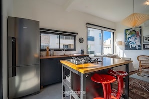 A modern kitchen with a stainless steel refrigerator, a gas stove, and a window overlooking the city. - Comfort in Condo w/ Pool in Campeche Hal10204 (Florianópolis)