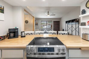 Une cuisine moderne dotée d’une cuisinière intégrée, de meubles blancs et d’un coin repas avec des chaises blanches.