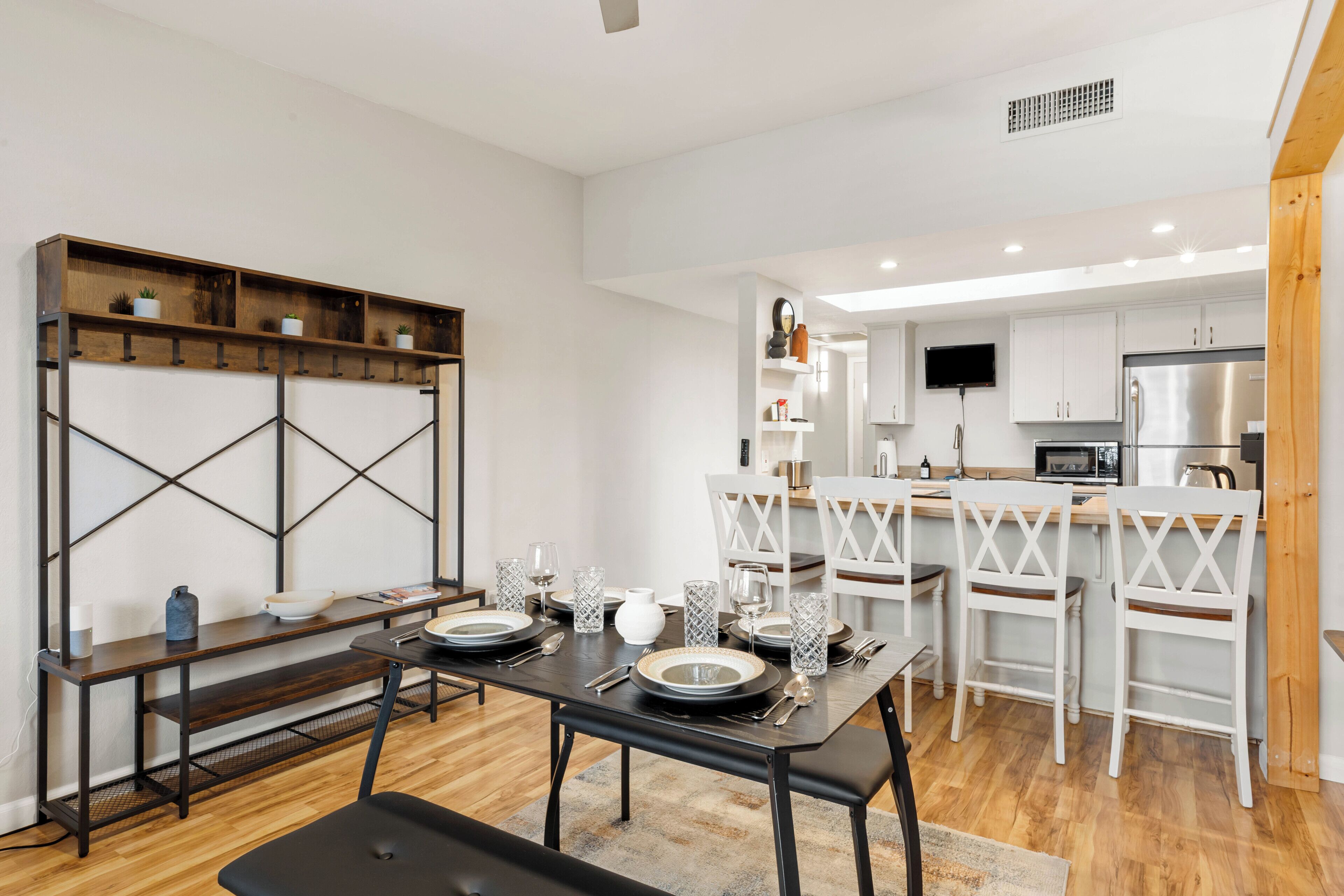 Une cuisine moderne avec des meubles blancs, un îlot central doté de sièges et un coin repas avec une table noire et des chaises blanches.
