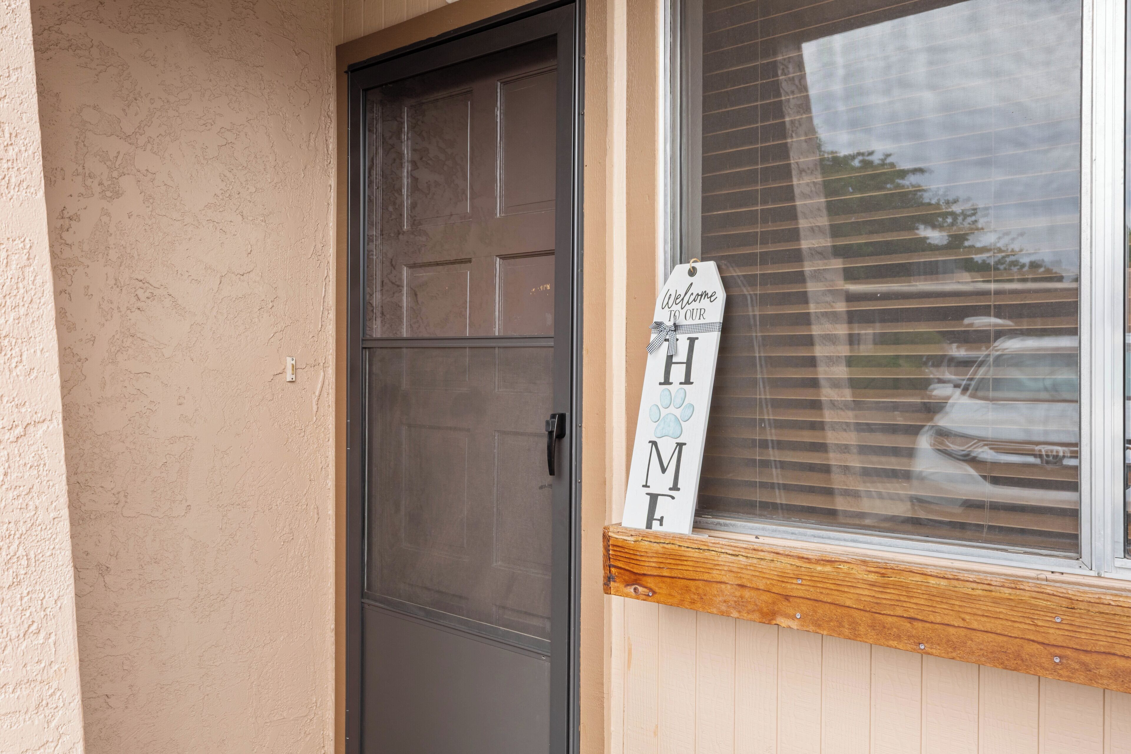 A door with a window above it, a wooden mailbox, and a welcome sign.