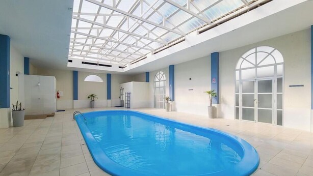 An indoor swimming pool with a skylight ceiling, tiled floor, and potted plants. - Apt in Condo w/ Pool in Ingleses Norte Ftm0106 (Florianópolis)