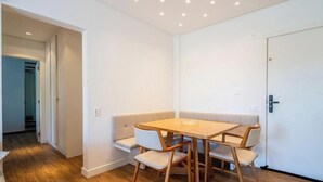 A room with a wooden dining table and bench seating, a door, and a hallway leading to another room. - Apt in Condo w/ Pool and Beach Access Eli0204 (Florianópolis)