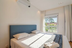 Ein Schlafzimmer mit einem Bett, einem Fenster mit Vorhängen und einer Klimaanlage.