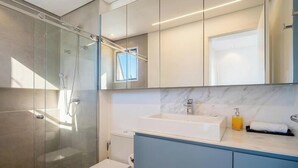 A modern bathroom with a glass-enclosed shower, a white sink, and a marble countertop. - Apt in Condo w/ Pool and Beach Access Eli0204 (Florianópolis)