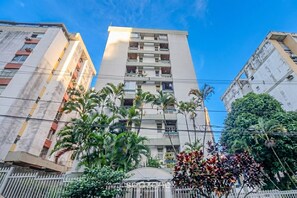 A multi-story building with balconies, surrounded by palm trees and a gated entrance. - Studio in Condo With Garage in Ondina Vdk0402 (Salvador)