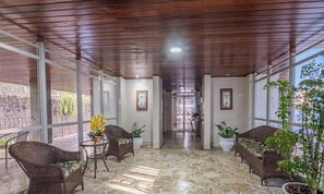 A covered outdoor area with wicker furniture, potted plants, and a stone floor. - Studio in Condo With Garage in Ondina Vdk0402 (Salvador)