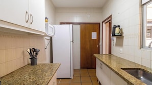 A compact kitchen with white cabinets, a white refrigerator, a microwave, and a coffee maker on the counter. - Apto in Condo w/ Pool & Ocean View Braga Srb0101 (Cabo Frio)