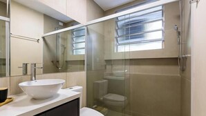 Un bagno moderno con cabina doccia in vetro, lavandino bianco e water.