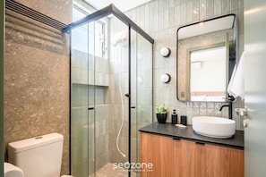 A modern bathroom with a glass shower enclosure, a wooden vanity, and a large mirror. - Studio in Building w/ View Downtown Eva0706 (Florianópolis)