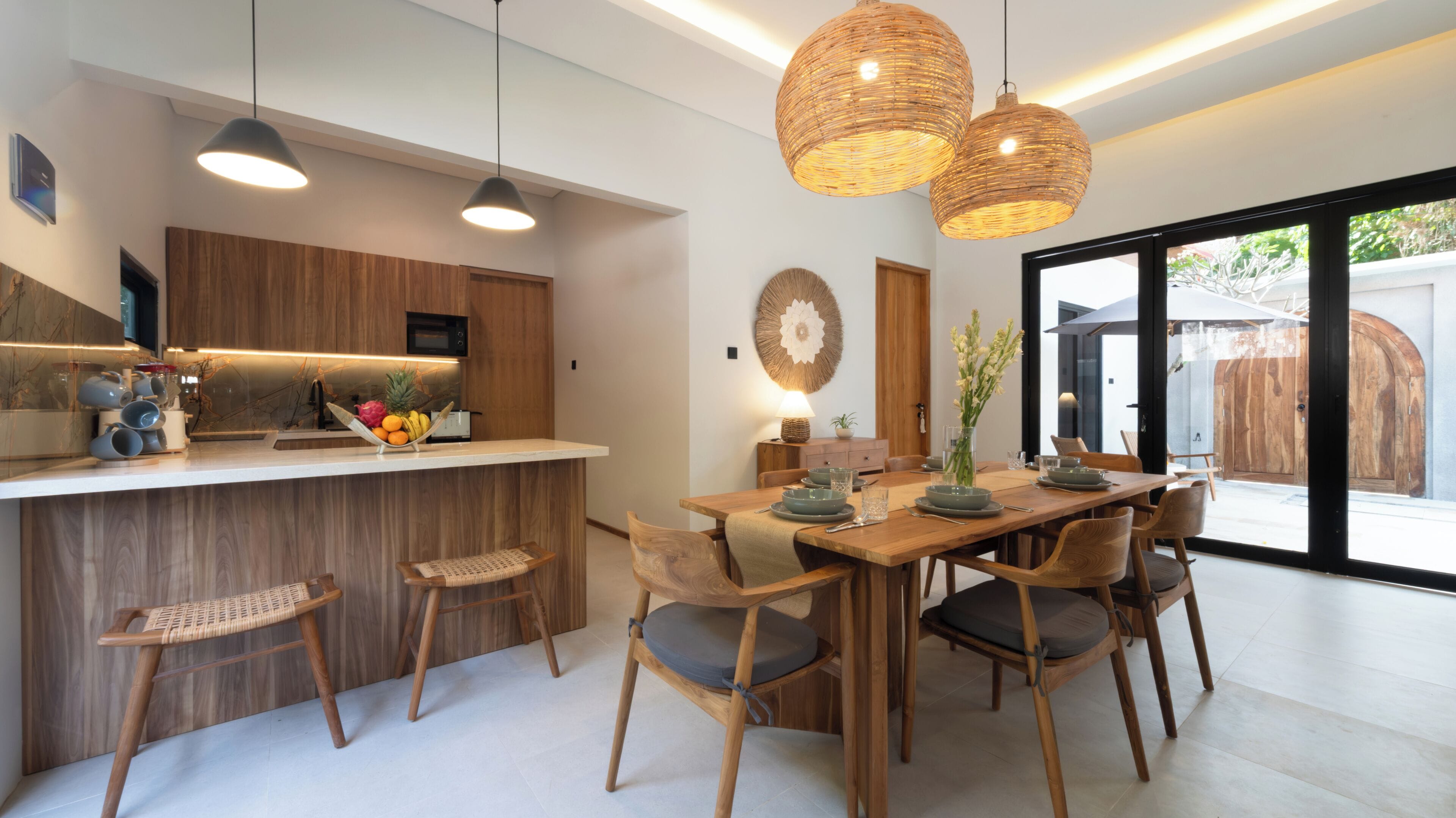 A modern kitchen with wooden cabinets, a dining area with a wooden table and chairs, and a large window with a view of the outdoors.