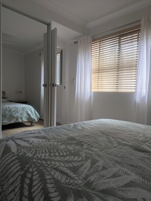 Ein Schlafzimmer mit einem Bett, einem Kleiderschrank und einem Fenster mit Jalousien.