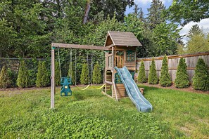 A wooden play structure with a slide and swings in a grassy backyard. - Modern Family Retreat Near Sea-tac, Marina & Seattle (Des Moines)