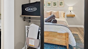 Ein Schlafzimmer mit einem Bett, einem Nachttisch, einer Lampe, einem Wandregal mit einer schwarzen Tasche und einem Fenster mit Blick.