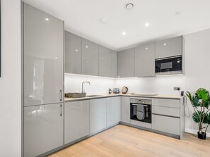A modern kitchen with grey cabinets, a microwave, a kettle, and a dishwasher. - Elephant & Castle by Interhome (London West End)