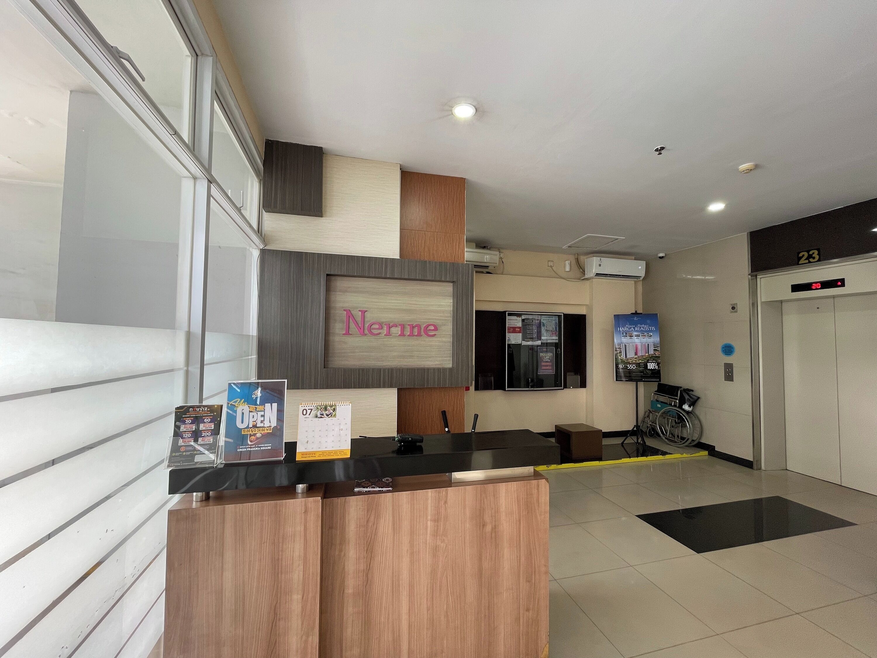 A reception desk with a wooden finish, a digital display, and a calendar.