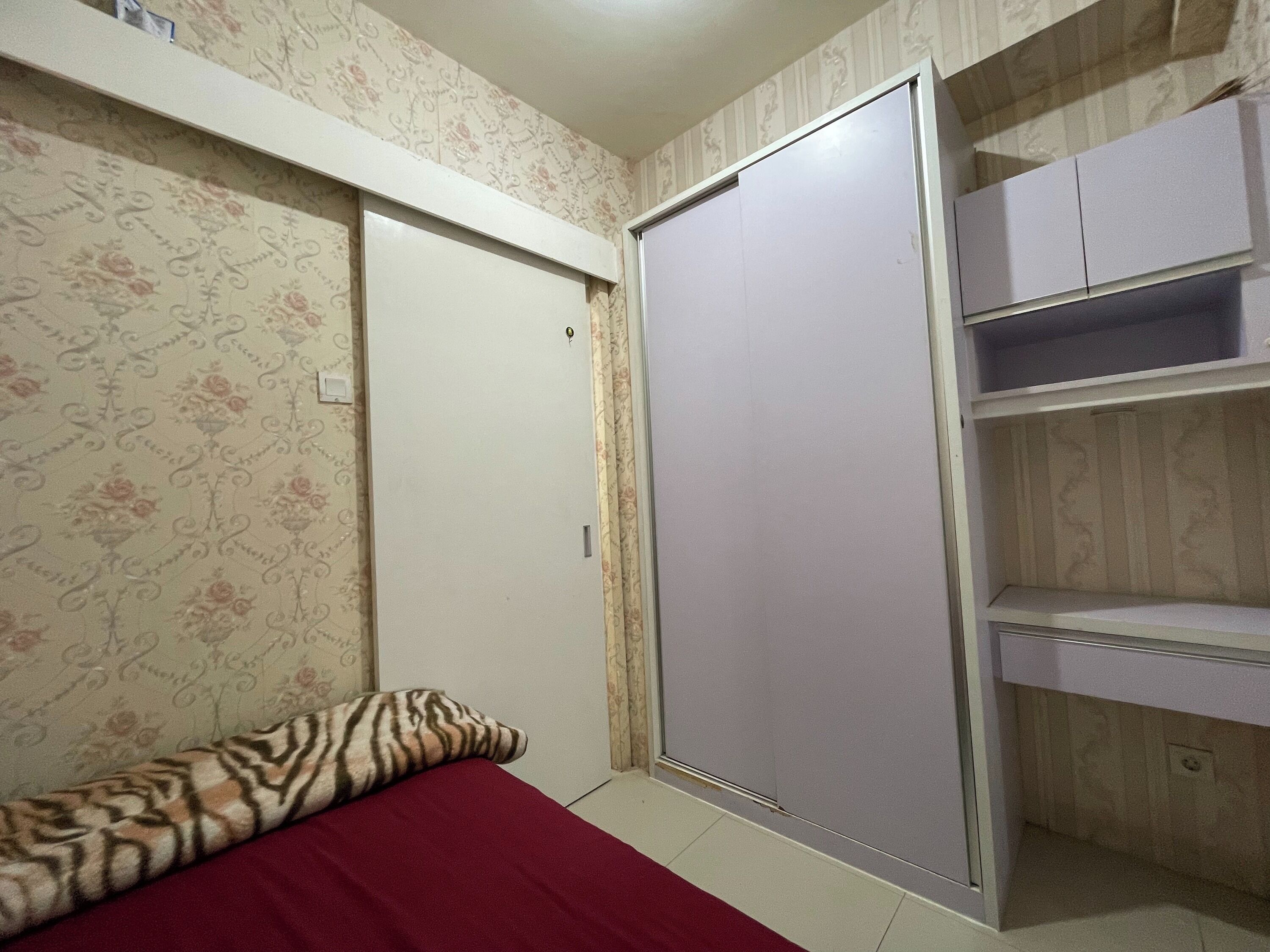 Um quarto com uma cama, um guarda-roupa e uma estante.