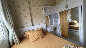 Een kamer met een bed, een kledingkast, een bureau en een spiegel.
