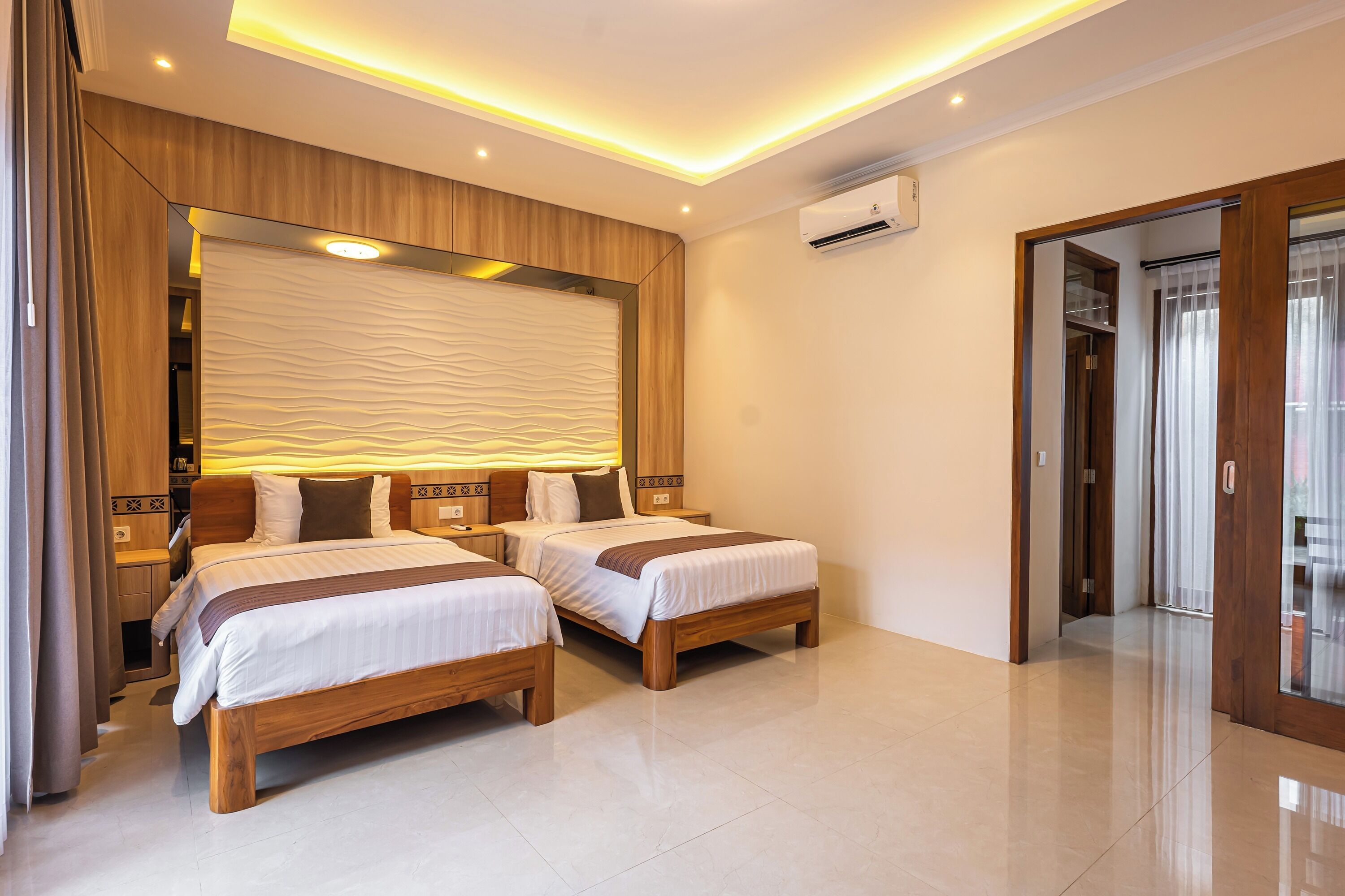 Une chambre d’hôtel avec deux lits en bois, un grand miroir et un design moderne au niveau du plafond.