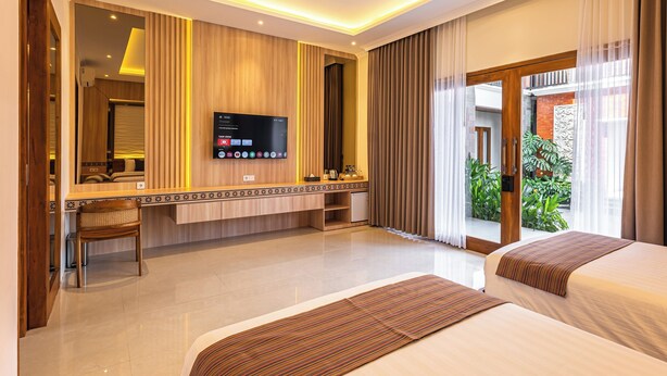 Een hotelkamer met een bed, een bureau, een televisie en uitzicht op groen.