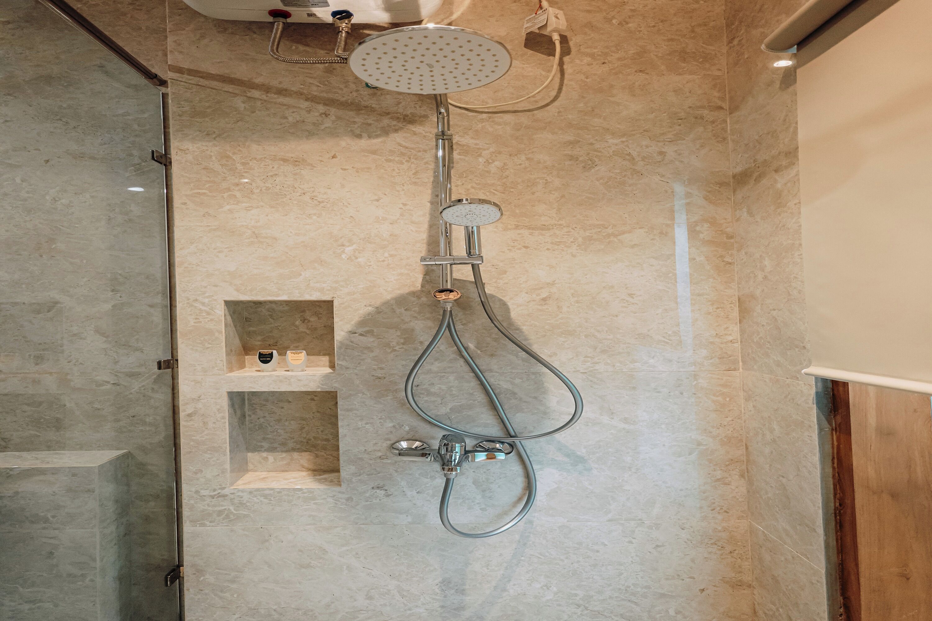Une douche équipée d’un pommeau de douche à main et d’un robinet fixé au mur.