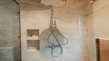 Une douche équipée d’un pommeau de douche à main et d’un robinet fixé au mur.