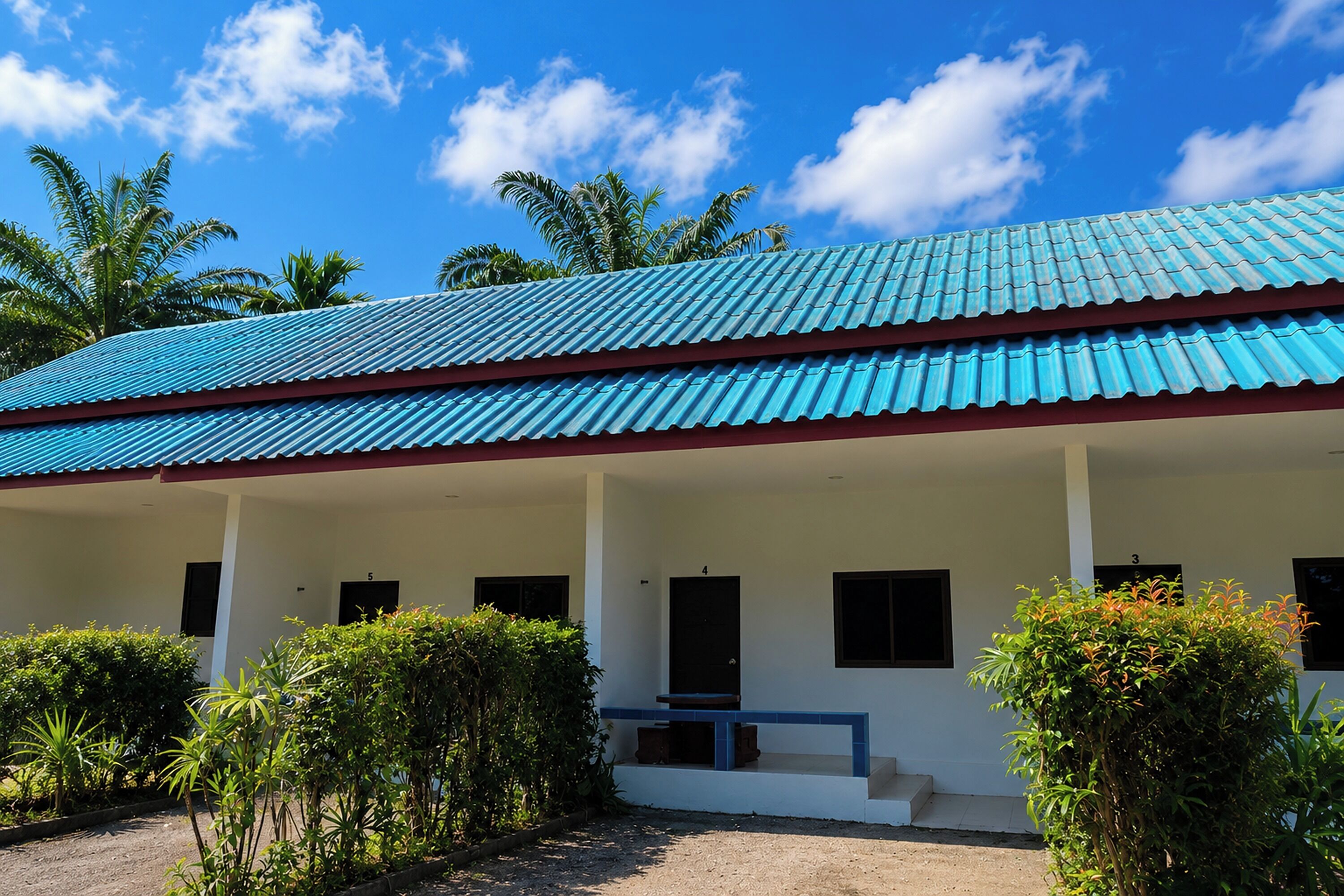 A building with a blue roof, white walls, and a covered porch with steps leading to the entrance.