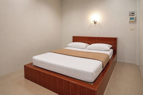 A single bed with a wooden headboard and a beige blanket, a wall-mounted light fixture, and a small picture frame on the wall. - 169 Home Resort (Krabi)