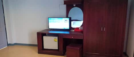 Quarto com uma cama, uma escrivaninha com computador, um espelho e um guarda-roupa.