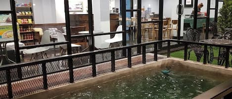 A dining area with tables and chairs, a water feature, and a view of the restaurant's interior.