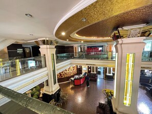 Un lobby de hotel de varios niveles con una imponente escalera, una recepción y un área de descanso.