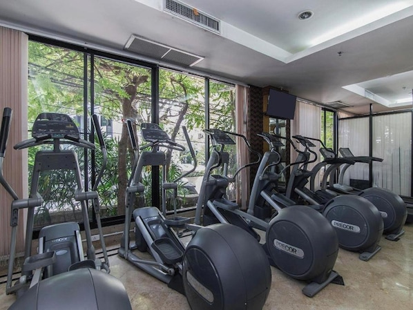Un gimnasio con cintas de correr, elípticas y bicicletas estáticas.
