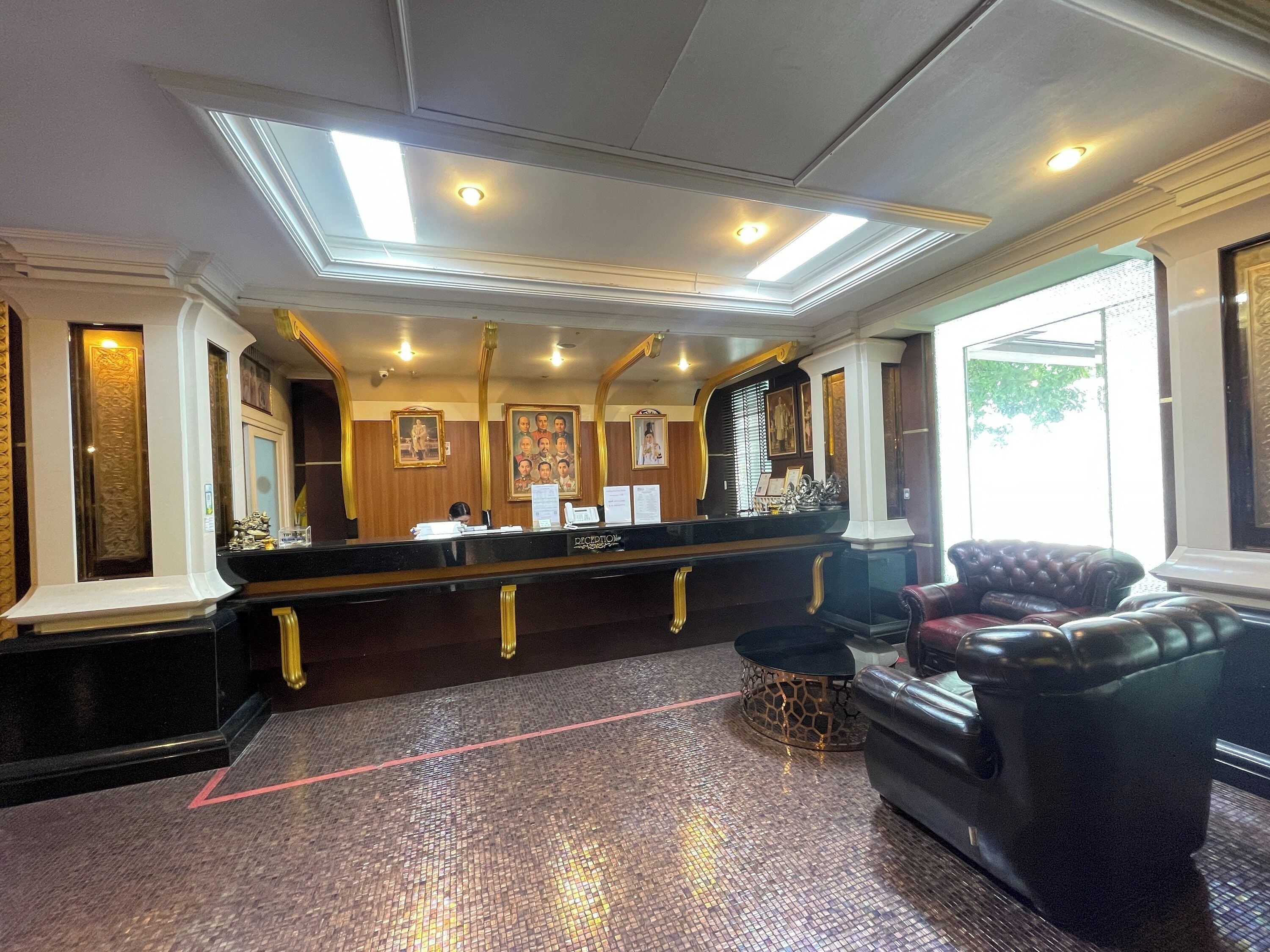A reception area with a black counter, a seating area with leather sofas, and a patterned floor.