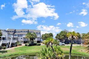 A multi-story residential building with balconies, a small pond, and palm trees. - Barrier Dunes 451 - 40 Lime Breeze (Port St. Joe)