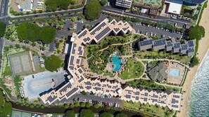 Um resort com vários edifícios, piscina e praia.