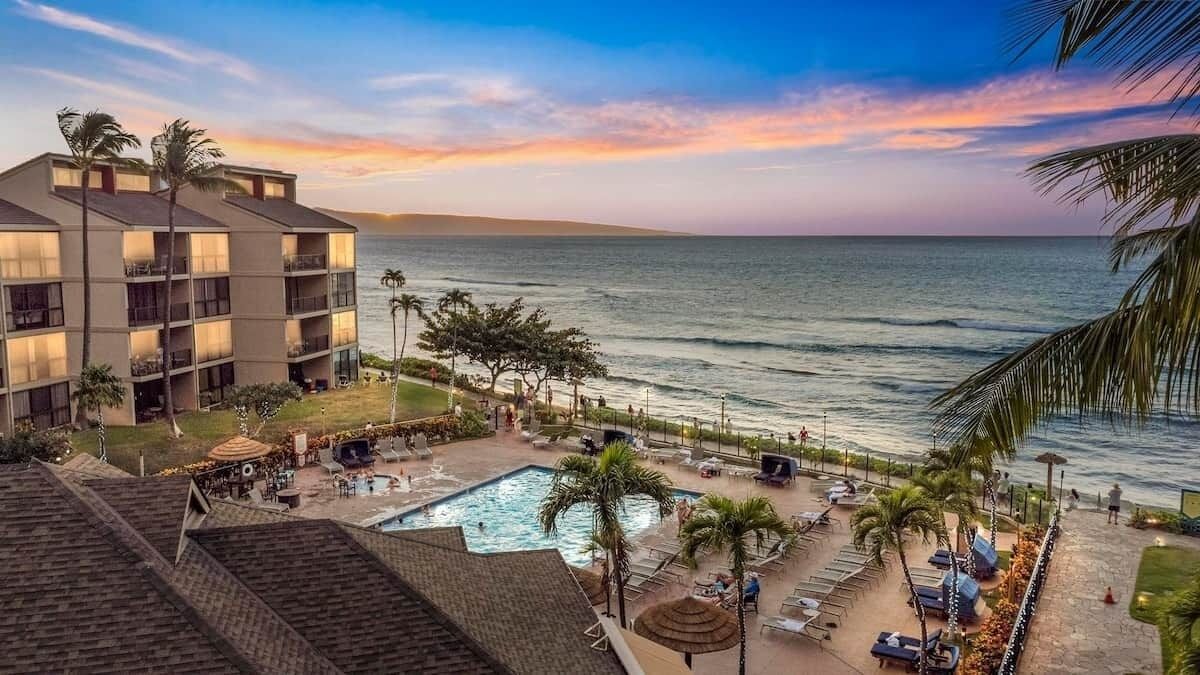 A hotel with a pool, lounge chairs, and a view of the ocean.