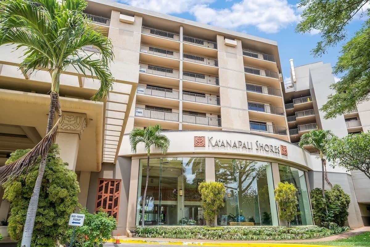 Un hôtel à plusieurs étages doté de balcons, une enseigne indiquant « Ka'anapali Shores », et un palmier au premier plan.