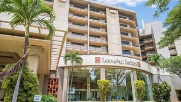 Un hôtel à plusieurs étages doté de balcons, une enseigne indiquant « Ka'anapali Shores », et un palmier au premier plan.
