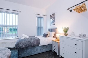 A modern bedroom with a bed, bedside table, lamp, and a view of the outdoors. - 3 BR House | Sleeps 7 | Free Parking | Fast Wi-Fi (Greater Manchester)