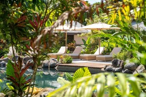 A pool area with lounge chairs and a covered seating area surrounded by tropical plants. - NALA Resort (Mission Beach)