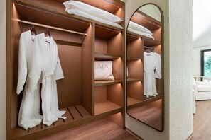 A walk-in closet with wooden shelving, a mirror, and hanging robes. - NALA Resort (Mission Beach)