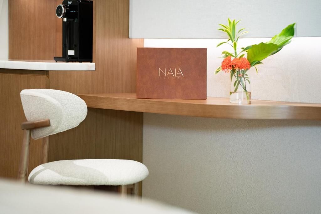 En receptionsdisk med et NALA-skilt, et kamera og en vase med blomster.