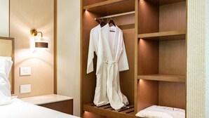 A hotel room with a wooden wardrobe, a bed, and a wall-mounted light fixture. - NALA Resort (Mission Beach)