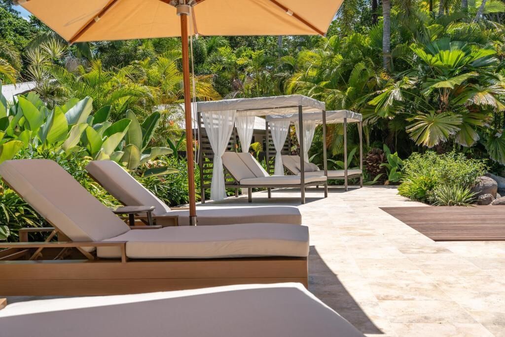 Zona de piscina con sillones de descanso y una sombrilla.