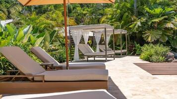 Zona de piscina con sillones de descanso y una sombrilla.
