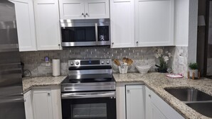A modern kitchen with white cabinets, stainless steel appliances, and a granite countertop. - Comfortable Home Near Disney ,Private Entrance & Free Parking (Davenport)
