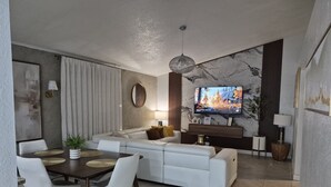 A modern living room with a sofa, dining table, and TV. - Comfortable Home Near Disney ,Private Entrance & Free Parking (Davenport)