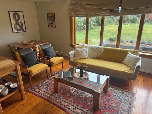 Een woonkamer met een bank, stoelen, een bijzettafeltje en een vloerkleed.